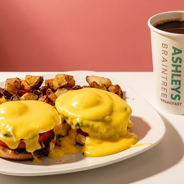 Two eggs Benedict with home fries and an Ashleys Braintree Breakfast coffee.